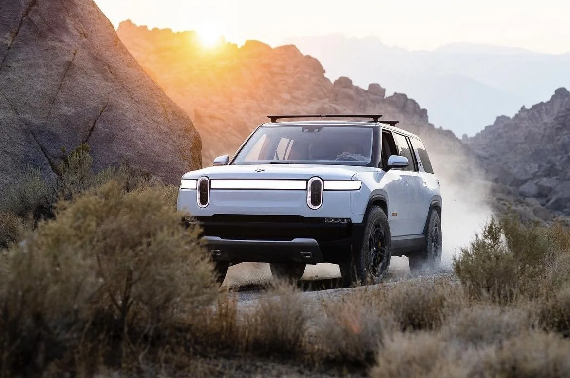 Rivian R1S Electric SUV Driving In Sunlit Desert Rocks